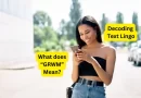 A young woman smiling while looking at her phone, with text overlayed that reads, "What does 'GRWM' Mean?" and "Decoding Text Lingo.